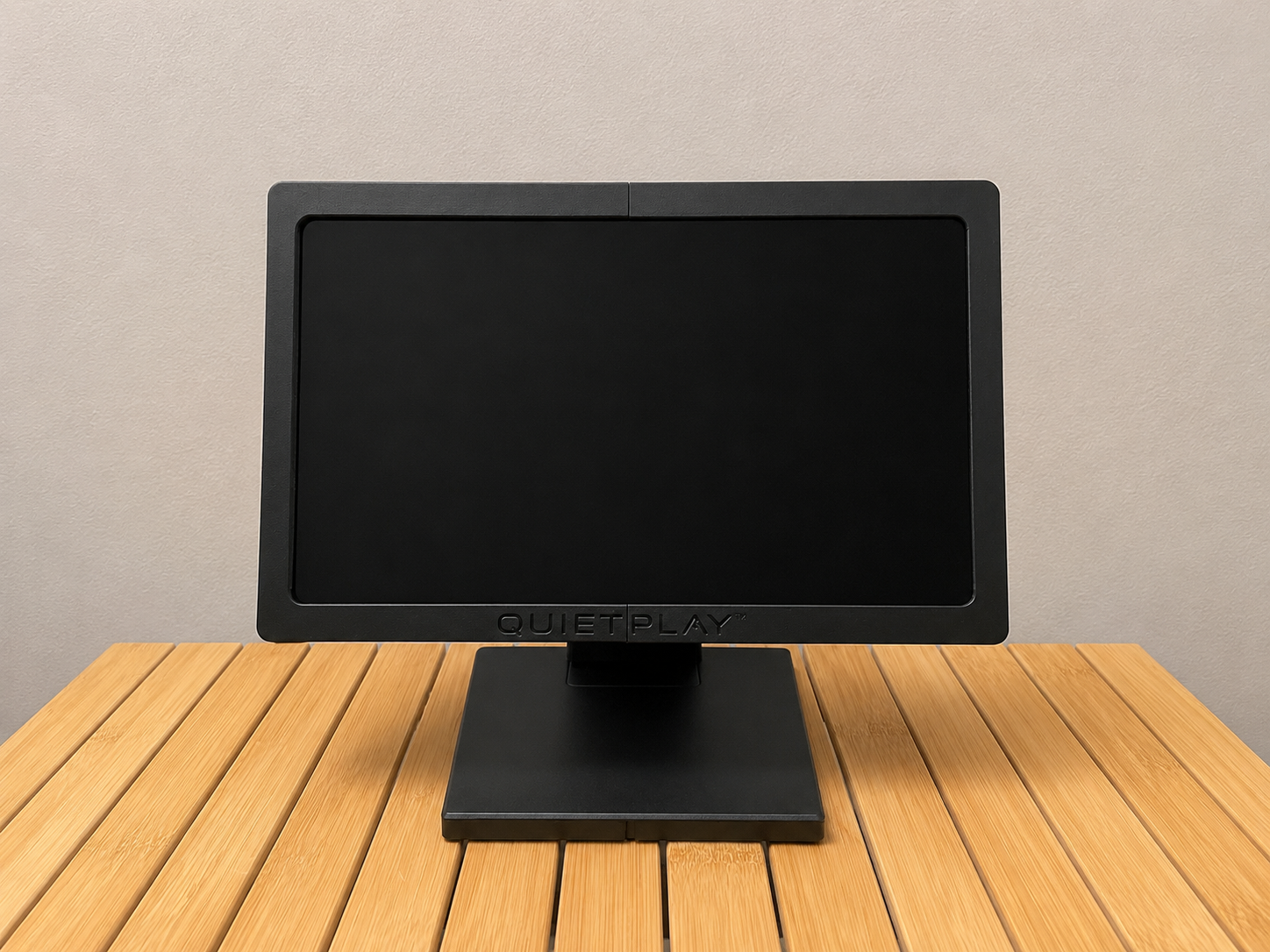 QuietPlay touchscreen entertainment device on its stand in a waiting room, showing a word search game on screen